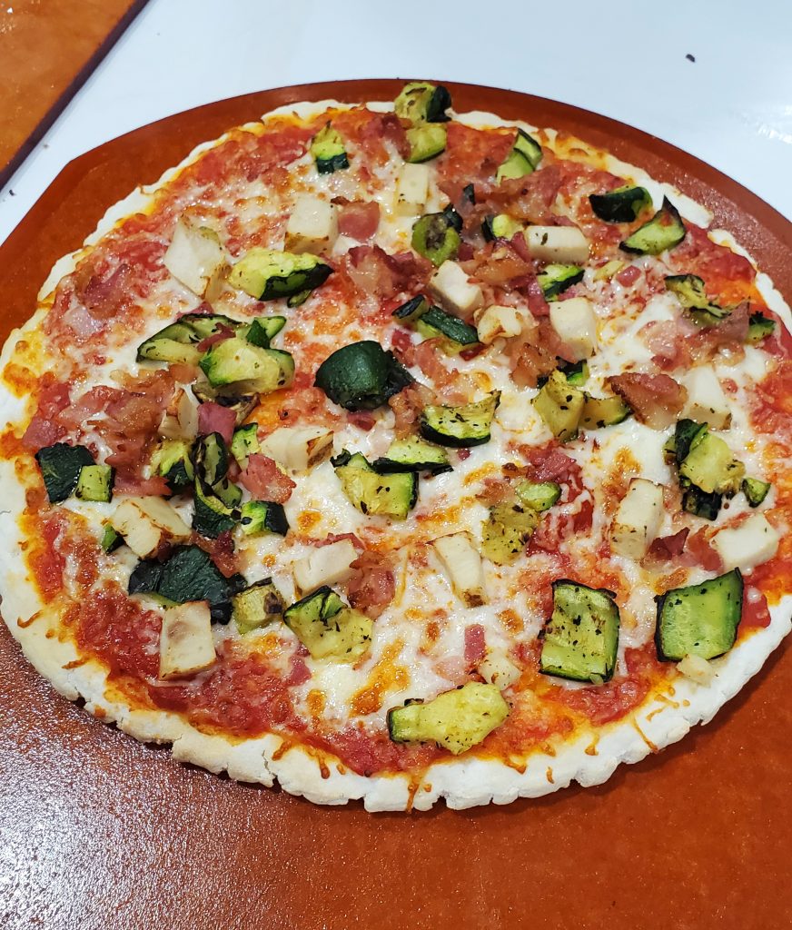 Gluten free pizza loaded with toppings and displayed on a wooden board